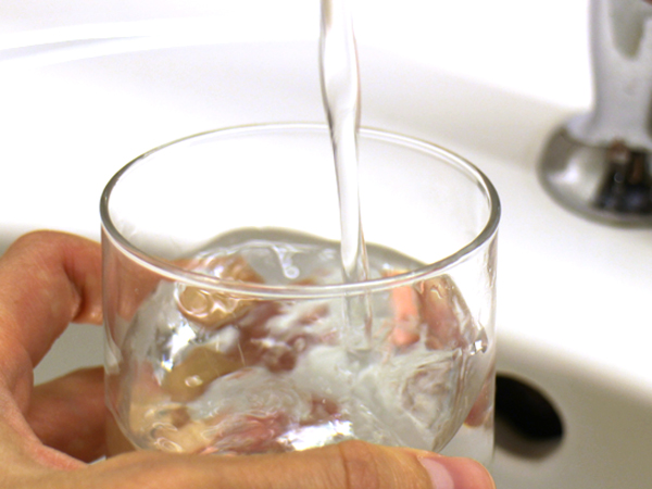 Wasser wird aus einem Hahn in ein Glas gefüllt